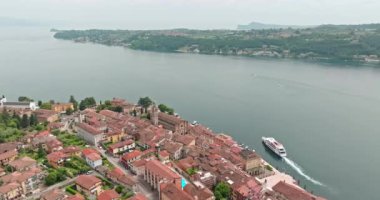İtalya 'daki Garda Gölü' ndeki Salo şehrinin havadan görünüşü. Bir tekne Dolomite Alpleri 'ndeki bir şehir yakınlarındaki bir gölün kıyısında yol alır, turistik geziler ve dinlenme yerleri. Yüksek kalite 4k görüntü