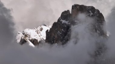 Rosengarten Grubu İtalya 'nın havadan görüntüsü. Bulutlu havada kayalık bir dağın tepesinde, karlı Dolomite Alplerinin inanılmaz doğası. Yüksek kalite 4k görüntü