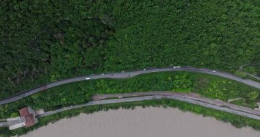Dağ yolunun güzel bir manzarasının havadan görüntüsü. Arabalar dağlık bir orman, seyahat ve turizm alanında bir yılan sineği boyunca yol alırlar. Yüksek kalite 4k görüntü