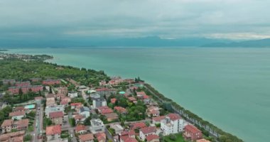 Hava manzaralı Garda Gölü Peschiera del Garda İtalya. Gölün kıyısındaki evler, doğa manzarası, turizm ve Alpler 'de dinlenme. Yüksek kalite 4k görüntü