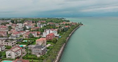Hava manzaralı Garda Gölü Peschiera del Garda İtalya. Rıhtımda yüzme havuzları olan güzel evler, bir turist kasabasının manzarası, Alpler 'de seyahat ve dinlenme yerleri. Yüksek kalite 4k görüntü