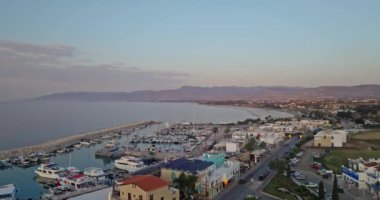Kıbrıs Rum Kesimi 'nin gün batımında limanda tekneleri ve yatları olan güzel bir marinanın havadan görüntüsü. Suda lüks tatiller. Yüksek kalite 4k görüntü