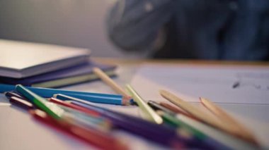 Cozy Childrens Room 'daki masada renkli kalemlerle resim çizen genç çocuk, Yaratıcı Öğrenme ve Sanatsal Gelişmeyi Evde Oyun ve Eğitimle Gösteriyor.