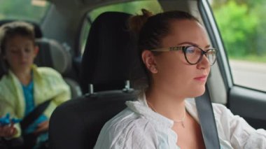 Anne oğlunu arabayla okula götürür. Araba koltuğunda oturan bir çocuk ailesiyle gider. Yüksek kalite 4k görüntü