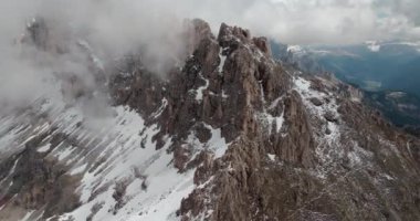 İtalya 'nın Dolomite Alpleri' ndeki Rosengarten grubunun hava görüntüsü. Kayalıklarla kaplı, dağın tehlikeli zirvesi karla kaplı ve bulutlarla örtülü. Yüksek kalite 4k görüntü