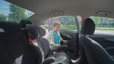 Anne ve oğul arabaya binip kemerlerini bağlayın. Çocuk araba koltuğunda oturur, güvenli bir yolculukta veya arabayla okula gider. Yüksek kalite 4k görüntü