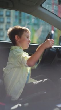 Bir çocuk, bir oğlan, bir arabanın direksiyonunda oturarak eğleniyor. Bir çocuk oyun oynarken araba sürüyormuş gibi yapar. Yüksek kalite 4k görüntü