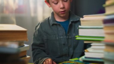 Okul çağındaki çocuk, evde oturup kitap okuyor ve ödev çocuğu üzerinde çalışıyor. Eğitim konseptine odaklanmış. Yüksek kalite 4k görüntü