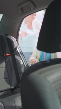 Anne, güvenli bir geziye ya da okul gezisine başlamadan önce küçük oğluna çocuk arabası koltuğunda oturması ve kemerini bağlaması için yardım ediyor. Yüksek kalite 4k görüntü