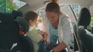 Anne, Oğul 'a Aile Seyahati ya da Okul Yolculuğu için Çocuk Arabası Koltuğu' na Yardım Ediyor. Yüksek kalite 4k görüntü