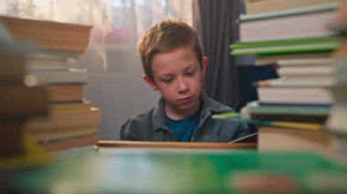 Evde Öğrenci Masası 'nda Çocuk Okuma ve Okuma. Elinde Eğitim ve Ödevlere Hazırlık Kitabı var. Yüksek kalite 4k görüntü