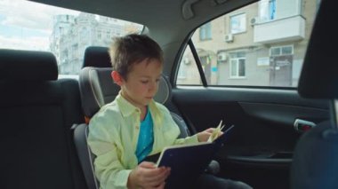 Çocuk, okula arabayla giderken ya da Aile Seyahati sırasında ebeveyn çocukla seyahat ederken Güvenli Araba Koltuğu 'nda kitap okuyor. Yüksek kalite 4k görüntü