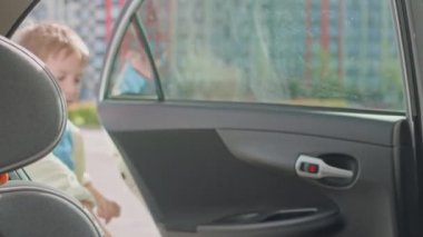 Bir çocuk, bir oğlan, çocuk oto koltuğuna oturur ve emniyet kemerini takar. Yolculukta ya da okulda güvenli bir yolculuk. Yüksek kalite 4k görüntü