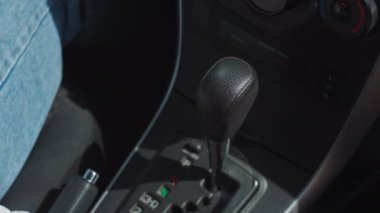 Otomatik viteste vites değiştiren bir kadının yakın çekimi. Kadın otomatik vites kolunu direksiyona geçirir ve uzaklaşır. Yüksek kalite 4k görüntü