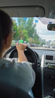 İş kadını, sabah trafiği sırasında işe giderken ellerini direksiyonda sıkıca tutarak şehir sokaklarında geziniyor. Yüksek kalite 4k görüntü