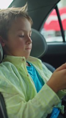 Bir çocuk seyahat ederken çocuk oto koltuğunda telefonda oynuyor. Yüksek kalite 4k görüntü