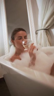 Güzel Kadın, uzun bir günün ardından romantik bir mum ışığında bir bardak şarapla küvette dinleniyor. Yüksek kalite 4k görüntü
