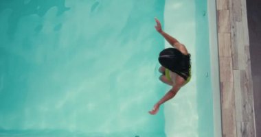 Havuza atlayan mayolu güzel bir kadının yavaş çekim videosu. Dinlenme ve rahatlama berrak suda yüzüyor, kız yüzüyor ve dalıyor. Yüksek kalite 4k görüntü