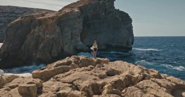 Okyanus kıyısındaki uçurumun tepesindeki bir kadının havadan görünüşü. Seyahat ve turizm özgürlük ve zevk hissi, güzel deniz manzarası. Yüksek kalite 4k görüntü