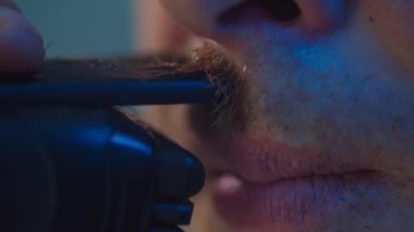 Makro videoda bir adam tıraş makinesiyle bıyık kesiyor. Evdeki banyoda tıraş olan bir güzellik uzmanı. Yüksek kalite 4k görüntü