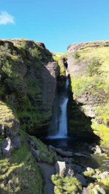 İzlanda 'da bir şelalenin doğa manzarası. Kayalıklardan bir dağ nehri akıyor, adanın turistik bir noktası. Yüksek kalite 4k görüntü