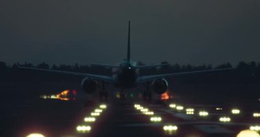 Bir yolcu uçağı indikten sonra aydınlık bir pistte seyahat ediyor. Bir uçağın havaalanına gece varışı. Yüksek kalite 4k görüntü