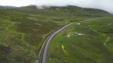 İzlanda Havacılık Manzarası 'nın dağlarında güzel bir sinematik yol. Beyaz bir araba yoldaki dağlara tırmanıyor, güzel kutup doğası. Yüksek kalite 4k görüntü