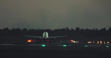 Aydınlatılmış bir havaalanı pistinden gece bir yolcu uçağı havalanıyor. Giden bir uçağın yavaş çekim videosu. Yüksek kalite 4k görüntü