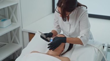 Bir kozmetolog, doktorların ofisinde bir aletle güzellik prosedürü uygular. Kozmetik güzellik ve sağlıklı kadınlar. Yüksek kalite 4k görüntü