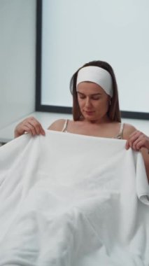 Güzel bir kadın hasta güzellik işlemleri için kozmetoloji sandalyesine oturur. Bir kızın sağlığı ve güzelliği, bir kozmetikçiyle randevu. Yüksek kalite 4k görüntü