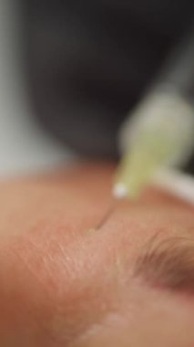Kozmetik uzmanı bir kadının yüz yenileme ameliyatı için şırınga iğnesi kullanıyor, cilt rengini düzeltiyor ve güzellik stüdyosundaki kırışıklıkları temizliyor. Yüksek kalite 4k görüntü