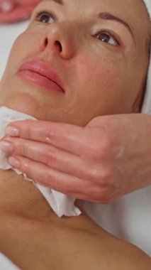 Güzellik enjeksiyonlarına hazırlık: Bir kozmetik uzmanı, profesyonel kozmetik işlemleri öncesinde, bir kadının yüzündeki anesteziyi nazikçe temizler. Yüksek kalite 4k görüntü