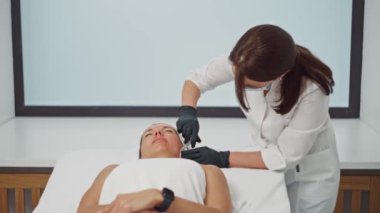 Bir güzellik uzmanı, bir kadının yüzüne enjeksiyon yapar. Kozmetolojide güzellik enjeksiyonlarının cildinin sıkılaştırılması ve tazelenmesi. Yüksek kalite 4k görüntü