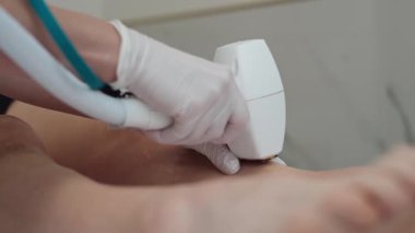 Güzellik salonunda kozmetik uzmanı kadın bacaklarına lazer epilasyonu uyguluyor. Cilt bakımı, kişisel bakım ve güzellik için profesyonel saç temizleme tedavisi. Yüksek kalite 4k görüntü