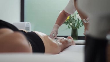 Bir güzellik uzmanı bir kadının bacaklarına tüy dökücü jel sürer. Profesyonel bir kuaför ve sağlık görevlisiyle Cosmelogy randevusu. Yüksek kalite 4k görüntü