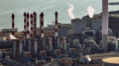 Kıbrıs Rum Kesimi elektrik santralinin hava manzarası: Akdeniz bölgesindeki hava ve denizi kirleten yakıt tankları, borular ve dumanlı sanayi manzarası. Yüksek kalite 4k görüntü