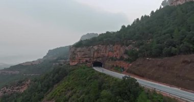Bir dağ yılanı boyunca tünelden geçen bir arabanın hava görüntüsü. Kayalık dağlara tırmanmak ve arabayla seyahat etmek tehlikelidir. Yüksek kalite 4k görüntü