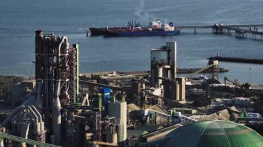 Kıbrıs Rum Kesimi elektrik santrali. Deniz kıyısında dumanlı borular, adanın rıhtımına yakın gemiler, hava kirliliği, ekoloji, sanayi manzarası. Yüksek kalite 4k görüntü