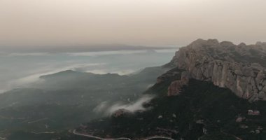 Şafak vakti Montserrat 'ın insansız hava aracı görüntüsü sisle kaplıydı: Katalonya, İspanya' daki dağların üzerinden büyülü gündoğumu, doğayı, dinginliği ve destansı seyahat noktalarını vurguluyordu. Yüksek kalite 4k görüntü