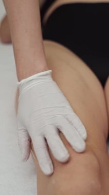 Estetik cilt bakımı yapan bir güzellik uzmanı lazer tüyü alınmadan önce kadın bacaklarına tüy dökücü jel sürer. Yumuşak cilt için profesyonel güzellik prosedürleri. Yüksek kalite 4k görüntü