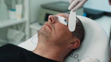 Güzellik uzmanı bir erkeğin yüzünü temizlemeden önce jel sürer. Kozmetolojide yaşlı bir adam için güzellik prosedürleri. Yüksek kalite 4k görüntü