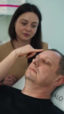 Kozmetik uzmanı yaşlı adamların yüzündeki sorunlu bölgelere işaret ediyor. Kozmetolojide yüz temizleme ve güzellik prosedürleri. Yüksek kalite 4k görüntü