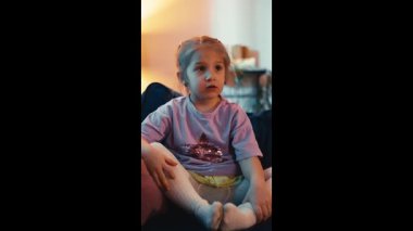 Beyaz kız evdeki kanepede televizyon izliyor. Childs video ve çizgi filmlere, mutlu çocukluklara ve oyunlara tepki veriyor. Yüksek kalite 4k görüntü
