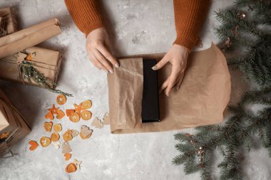 Bir kızın ellerinin Noel hediyesi ya da doğum gününü gri beton bir masada kutlarken, arka planda bir Noel ağacı ve ışıklar, yeni yıla hazırlık konsepti, mutlu noeller, yeni yıl 2023