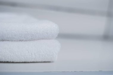Stack of clean soft white towels on table against light grey background. Space for text