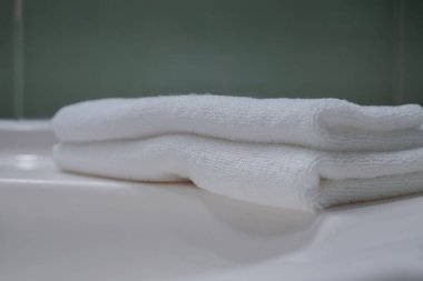 Stack of fresh towels, face roller and cream on countertop in bathroom