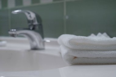 Stack of fresh towels, face roller and cream on countertop in bathroom