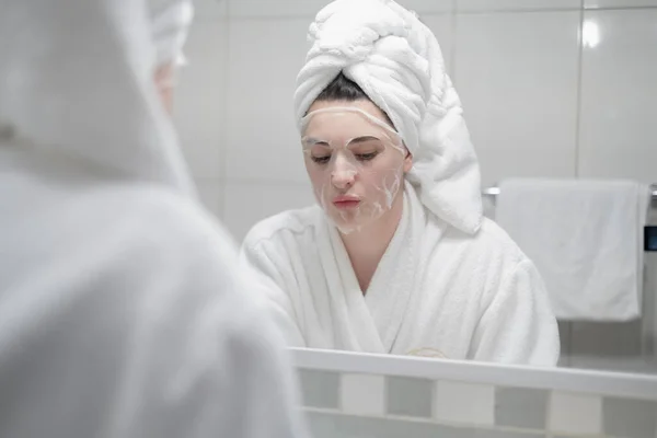 Young Caucasian Woman White Bathrobe Towel Her Head Removes Moisturizing — Fotografia de Stock