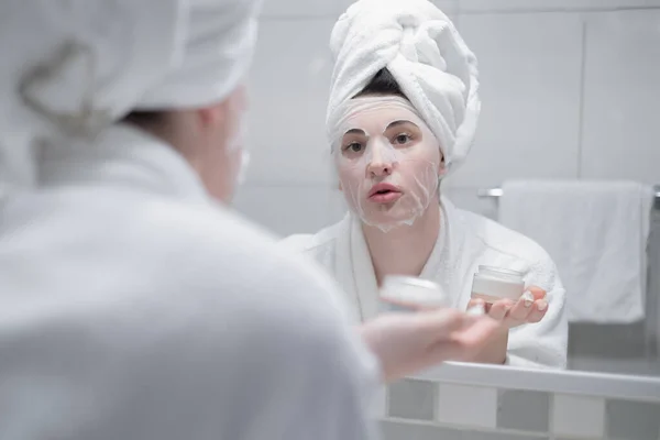 머리에 수건을 거울에 여성은 하루를 마감하는 크림을 적용하고 주름을 예방하고 — 스톡 사진