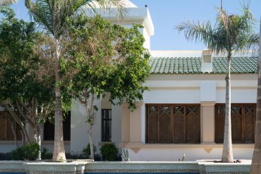Palm trees against white home by the beach with blue sky and sand